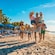 A family with young children playing on the beach near umbrellas and lounge chairs